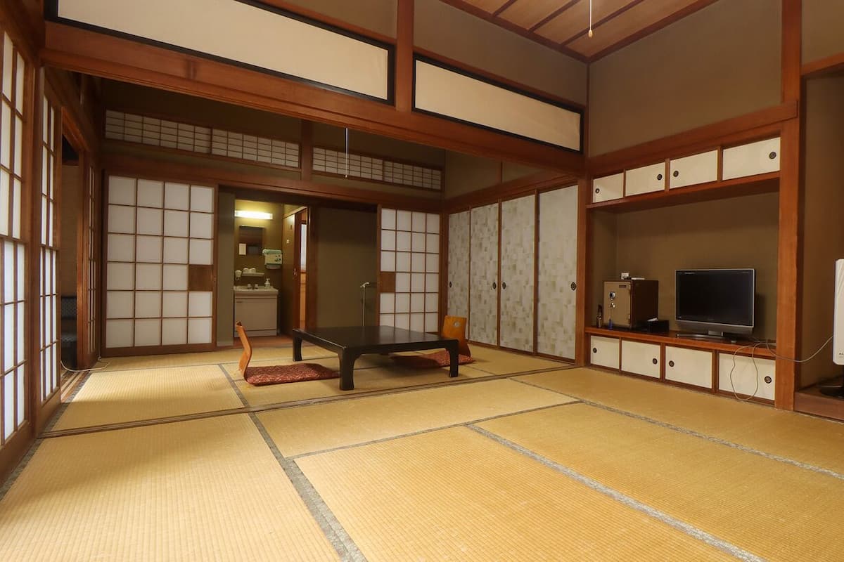 Een traditionele Japanse kamer met tatami vloeren, een lage tafel, een televisietoestel en bergkasten.
