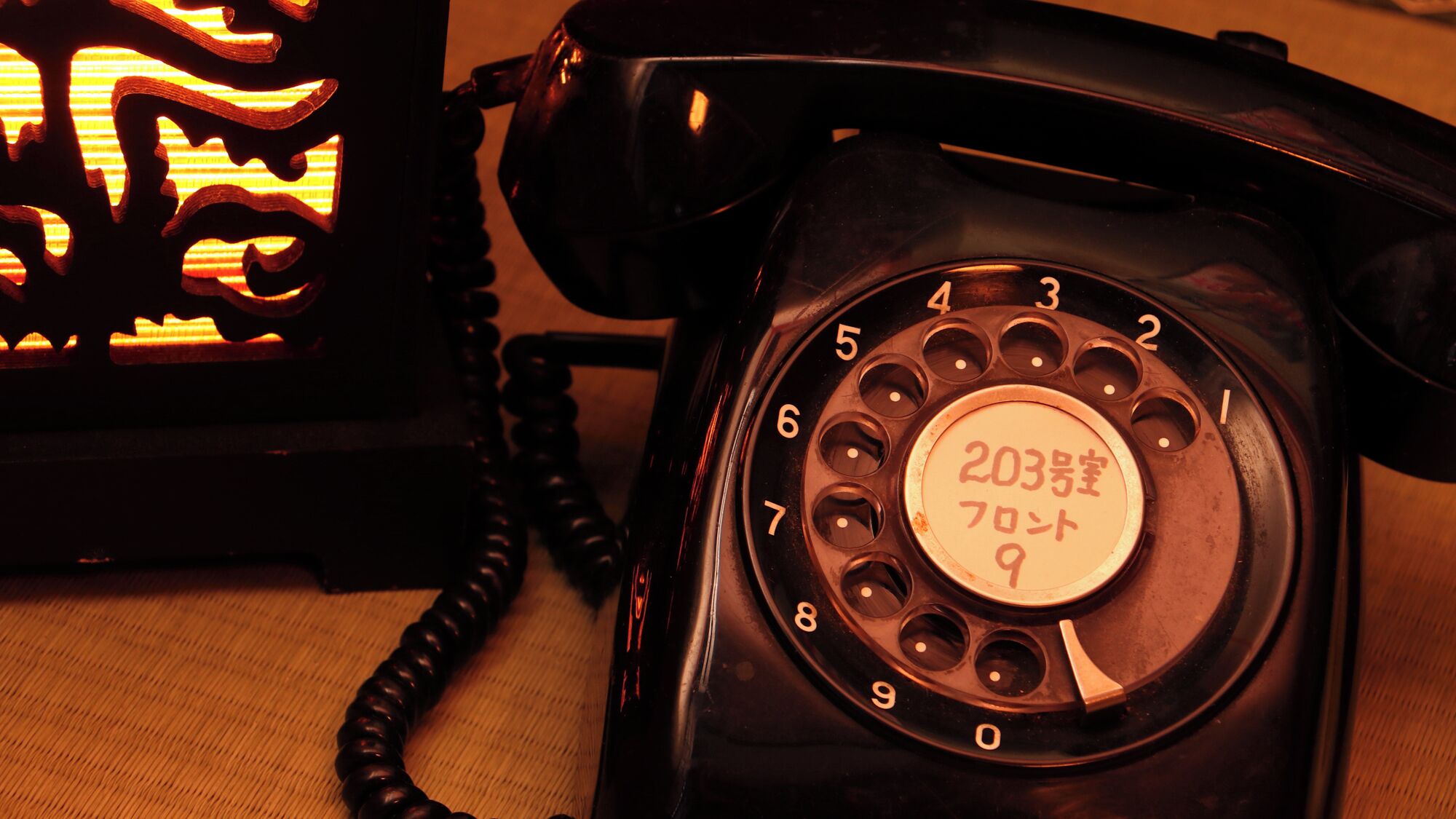 A rotary dial telephone with a circular dial pad and a label with Japanese characters.