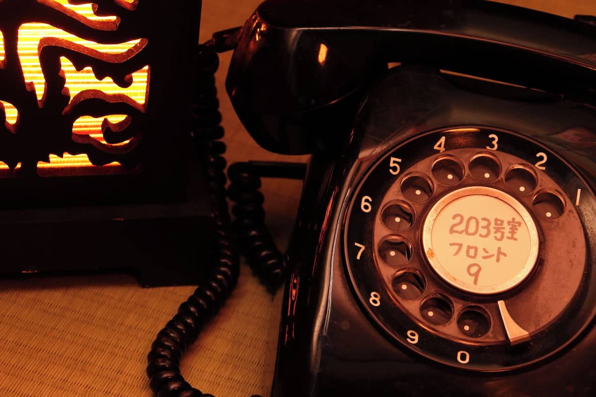 Een draaischijf telefoon met een ronde cijferschijf en een label met Japanse karakters.