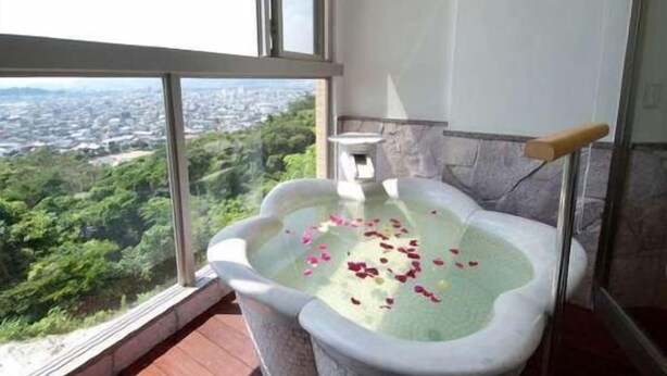 A bathtub with rose petals on a balcony with a city view. - Sunhills Mikawawan (Gamagori)