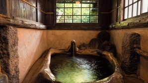 A stone bathtub with a window above it. - Yunoyado Irifune (Aso)