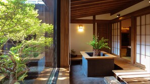A traditional Japanese room with tatami flooring, a low wooden table, a potted plant, and a sliding door leading to another room. - Yunoyado Irifune (Aso)