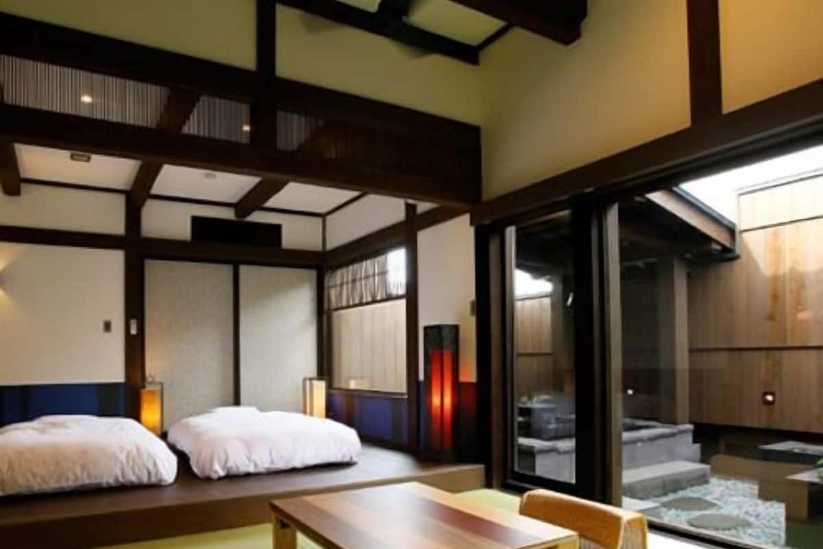 A traditional Japanese room with tatami flooring, a low wooden table, and a sliding door leading to a balcony.