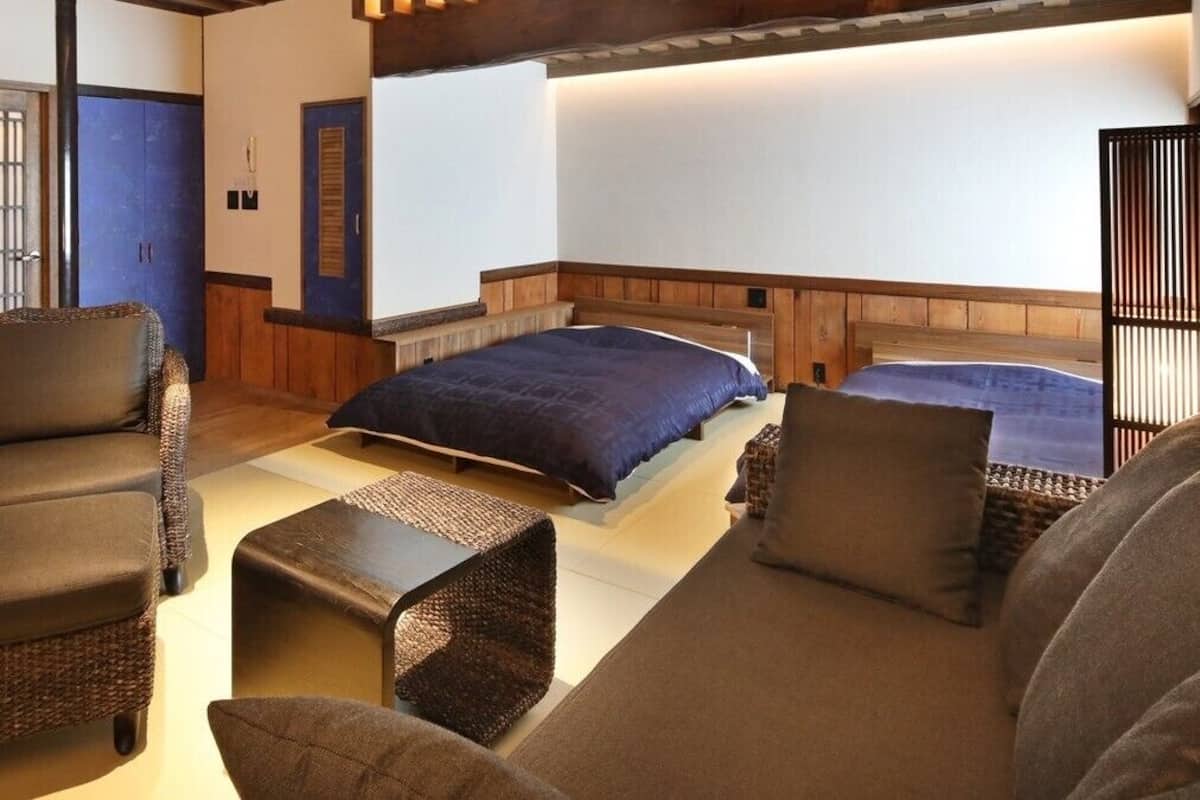 A room with a bed, two sofas, a chair, and a small table.