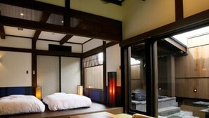 A traditional Japanese room with tatami flooring, a low wooden table, and a sliding door leading to a balcony. - Yunoyado Irifune (Aso)