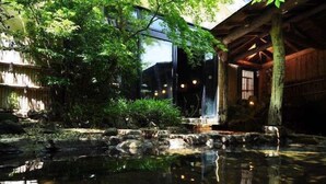A tranquil garden with a pond, wooden structures, and lush greenery. - Yunoyado Irifune (Aso)