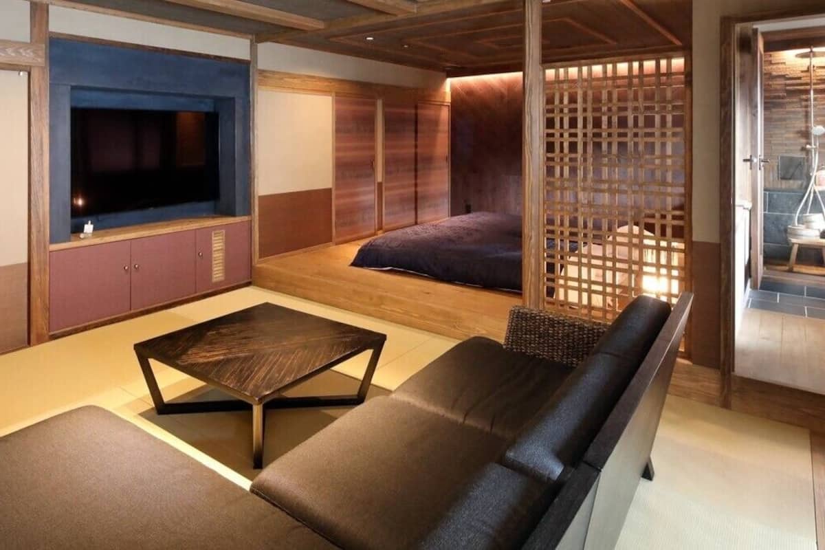 A room with a sofa, a coffee table, a TV, and a sliding door leading to a bathroom.