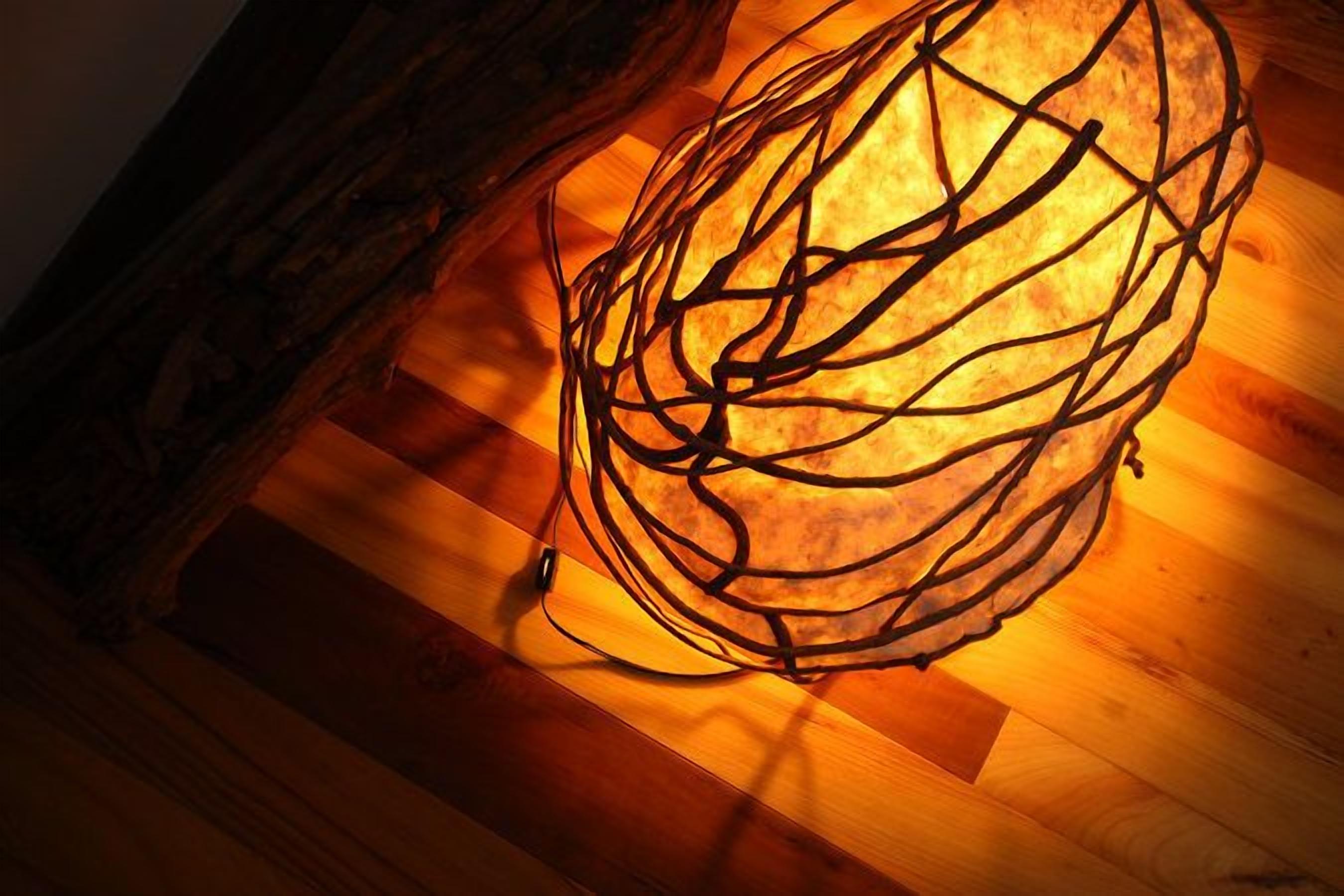 A spherical light fixture with a complex wire design on a wooden floor.