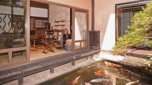 A koi pond with a wooden deck, a seating area with chairs, and a stone wall. - Yunoyado Irifune (Aso)