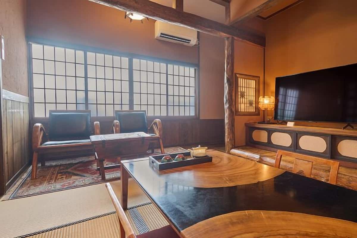 A traditional Japanese-style room with tatami flooring, a low table, and a television on a wooden stand.