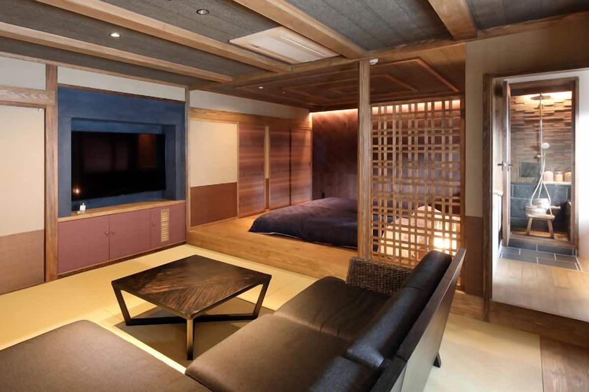 A modern living room with a flat-screen TV, a sofa, a coffee table, and a wooden partition.