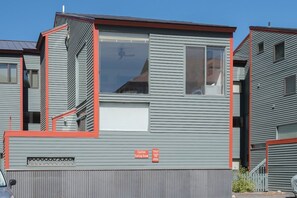 A modern multi-story residential building with a grey exterior and red accents.