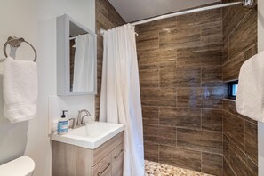 A modern bathroom with a shower, a sink, and a mirror.