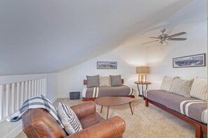 A loft-style bedroom with a bed, two sofas, a coffee table, and a ceiling fan. - Telluride Lodge Condo 323 (Telluride)