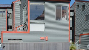 Un edifici modern amb façana gris i detalls vermells, i un senyal de precaució per la neu.