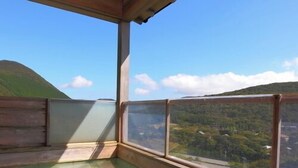 Una piscina de madera con vistas a una colina verde y un cielo despejado.