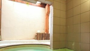 Una piscina con borde curvo, pared de azulejos y un pequeño banco de madera.