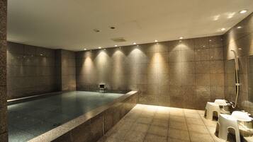 A modern bathroom with a large bathtub, two sinks, and a shower area.