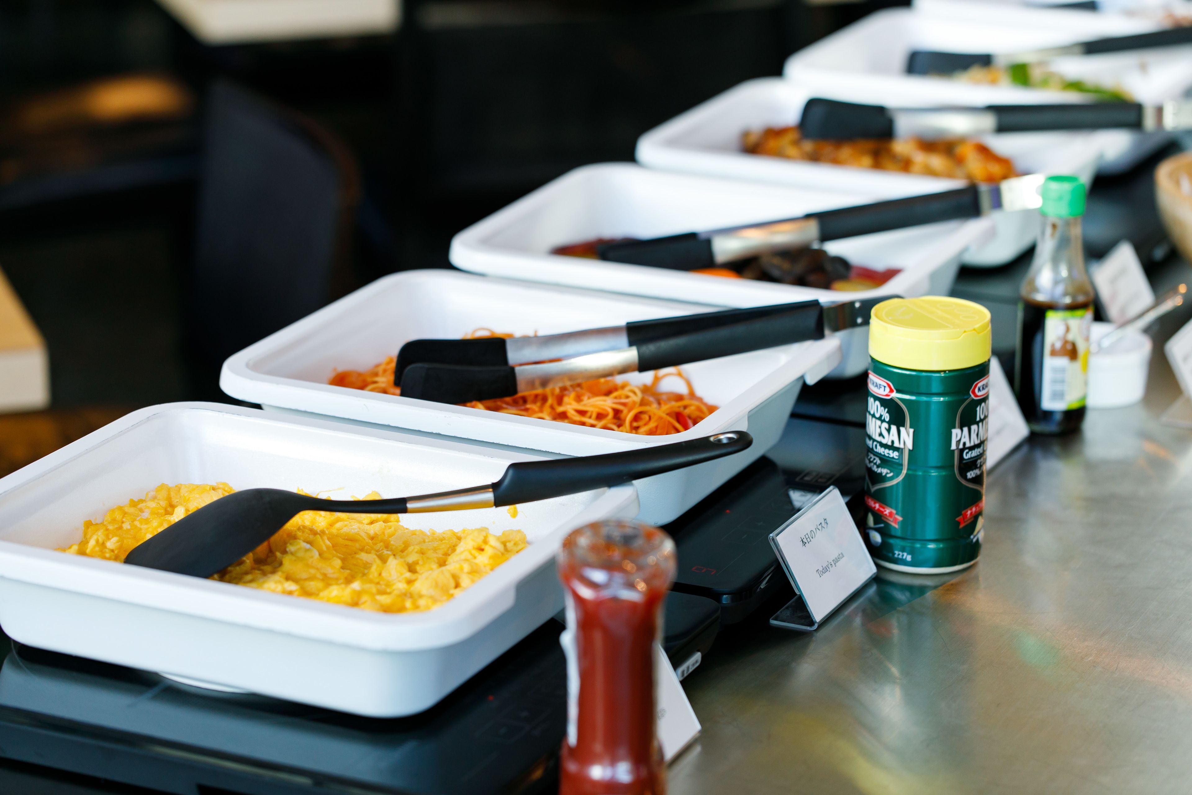 A buffet table with various food dishes and condiments.