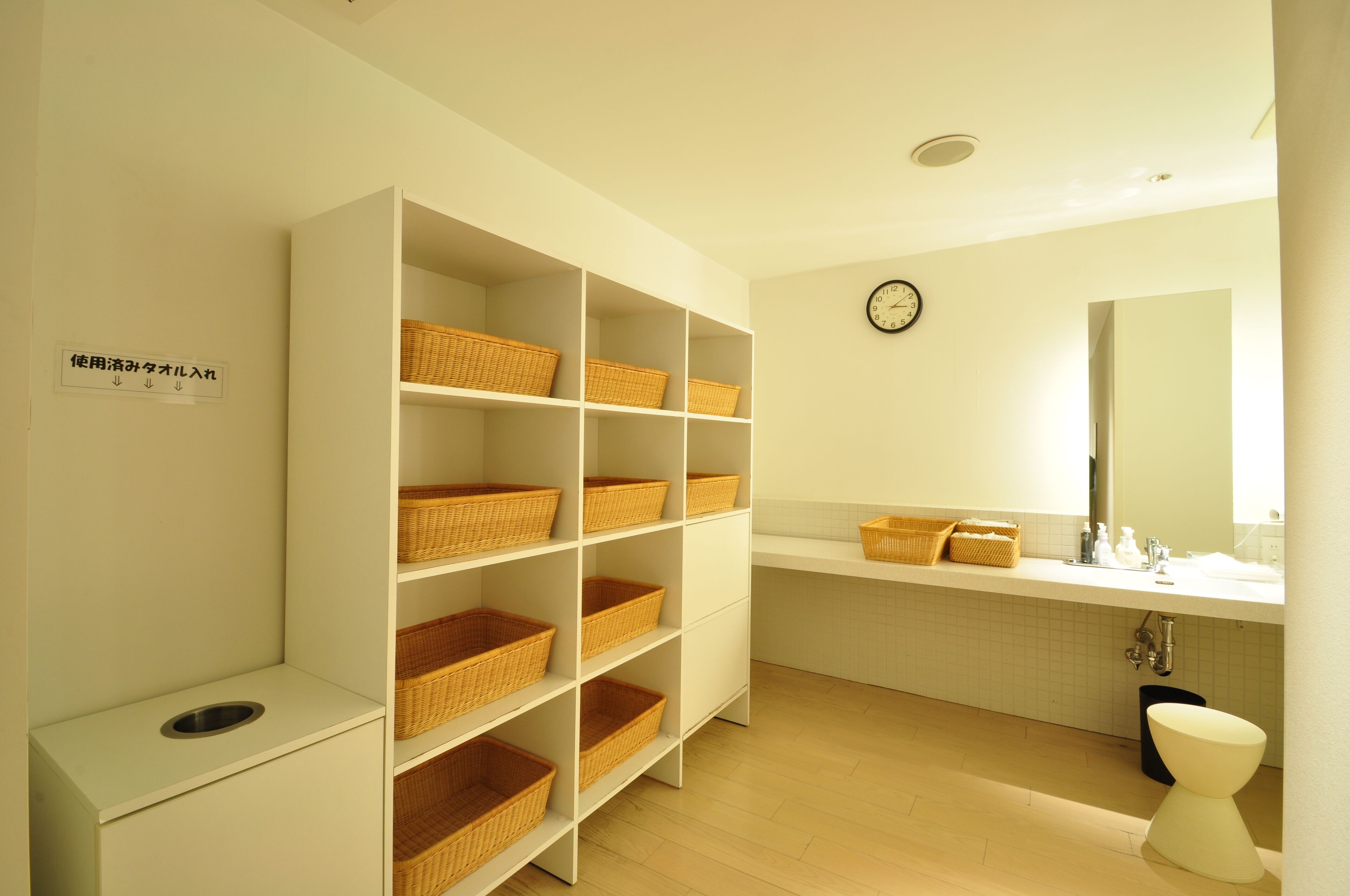 A bathroom with white shelves, wicker baskets, a sink, and a toilet.