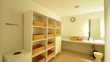 A bathroom with white shelves, wicker baskets, a sink, and a toilet.