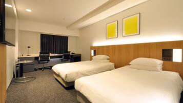 Ein Hotelzimmer mit zwei Betten, einem Schreibtisch, einem Stuhl und einem Fernseher.