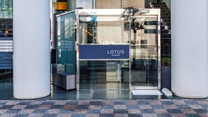 A modern building entrance with a glass door and a sign reading "LOTUS RESTAURANT". - The Grand Palace (Tokushima)