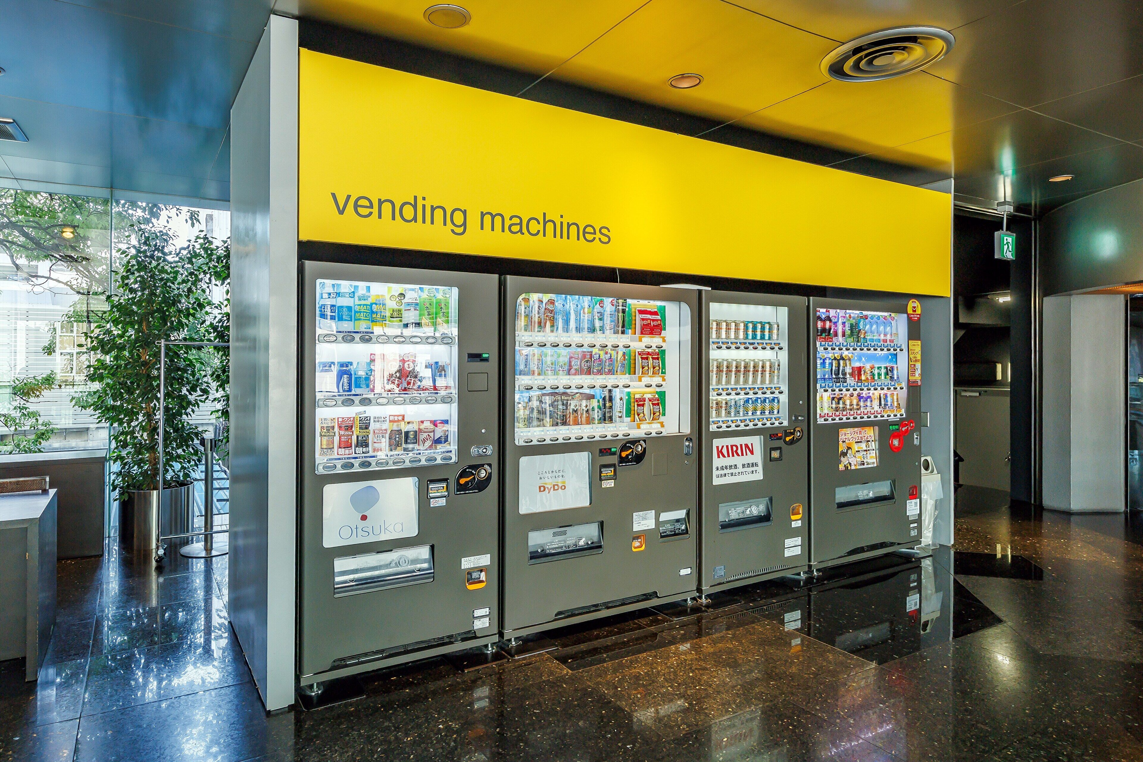 A row of vending machines with a yellow sign above them.