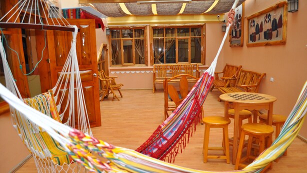 Una habitación con hamaca, muebles de madera y ventanas amplias.