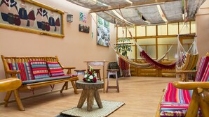 Una habitación amplia con muebles de madera, una hamaca y obras de arte en las paredes.