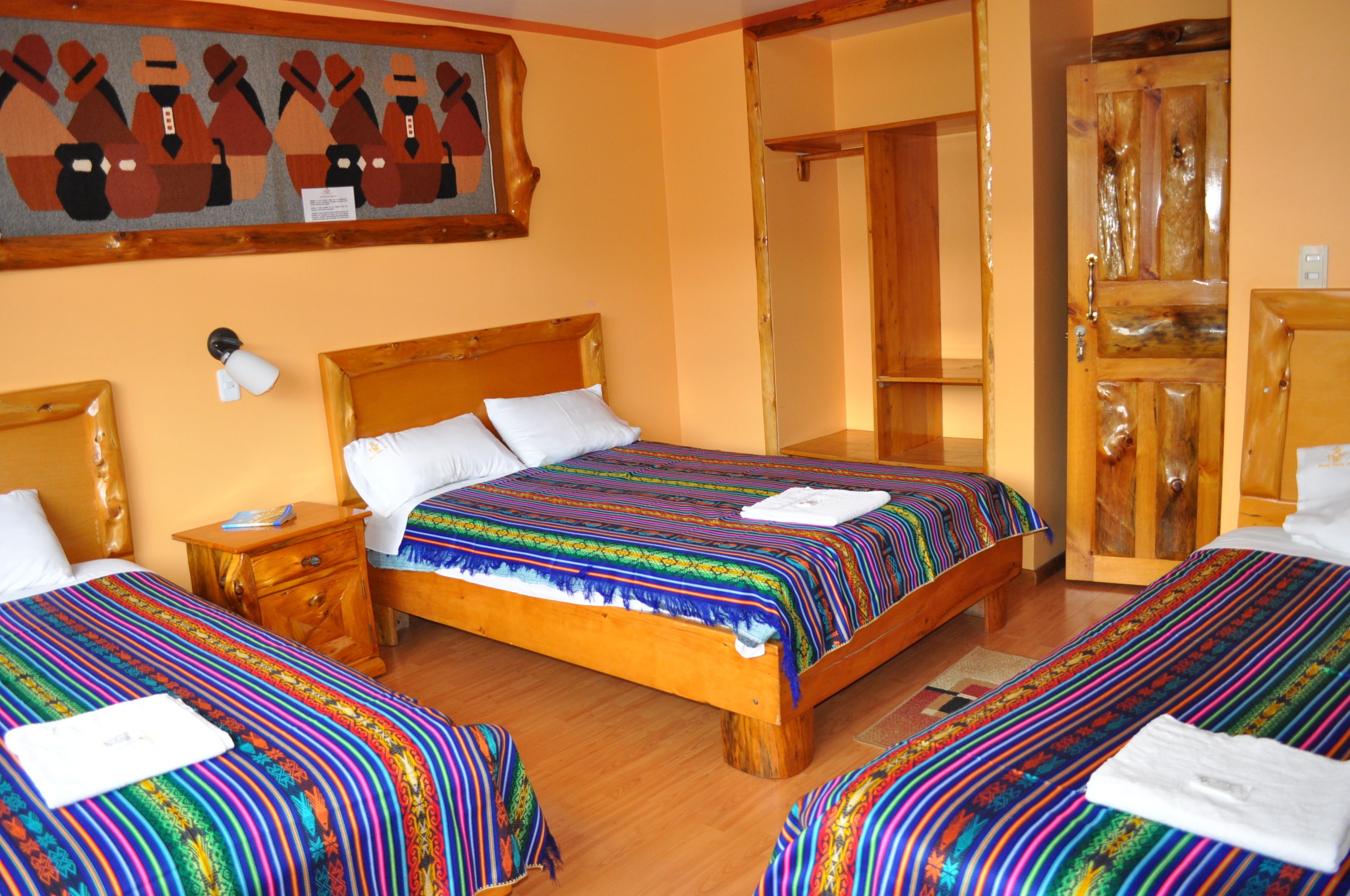 Una habitación de hotel con dos camas individuales, cabeceros de madera, un armario de madera y un cuadro en la pared.