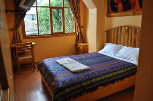 A bedroom with a wooden bed, a chair, a nightstand, and a window with curtains.