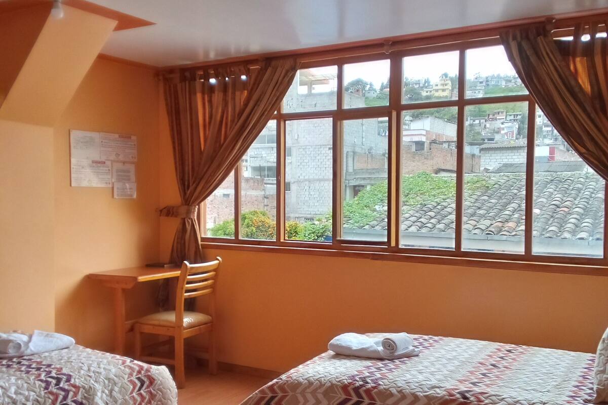 A hotel room with two beds, a desk, and a chair.