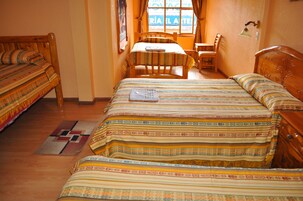 A room with two wooden beds, a wooden table, and a chair.