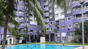 A swimming pool surrounded by a multi-story building with balconies, palm trees, and a gated entrance. - Gateway Malaysia - Johor Bahru (Johor Bahru)
