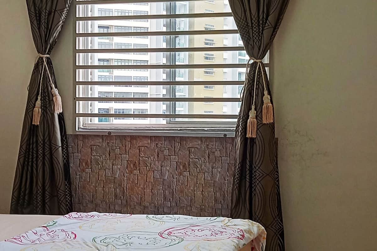Een slaapkamer met een bed, gordijnen, een raam en een bakstenen muur.