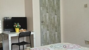 A room with a desk, a chair, a television, a potted plant, and a bed with a patterned bedspread. - Gateway Malaysia - Johor Bahru (Johor Bahru)
