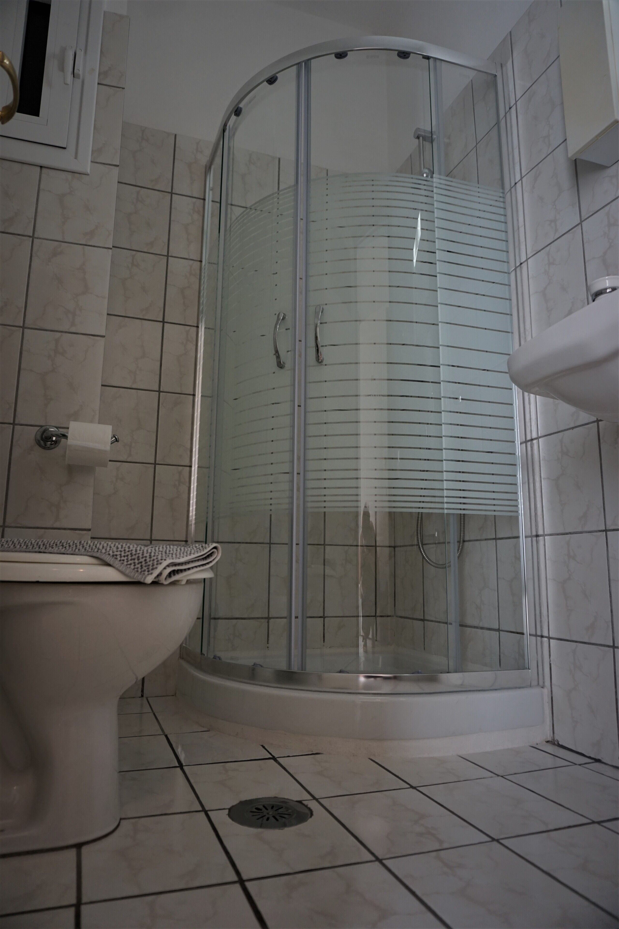A bathroom with a glass-enclosed shower, a toilet, and a sink.