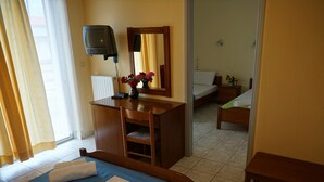 Ein Hotelzimmer mit einem Bett, einem Schreibtisch, einem Sessel, einem Fernseher und einem sichtbaren Badezimmer hinter einer geöffneten Tür.