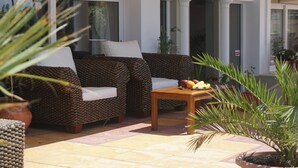 Eine Terrasse mit zwei Sofas, einem kleinen Tisch mit Früchten und Blumentöpfen.