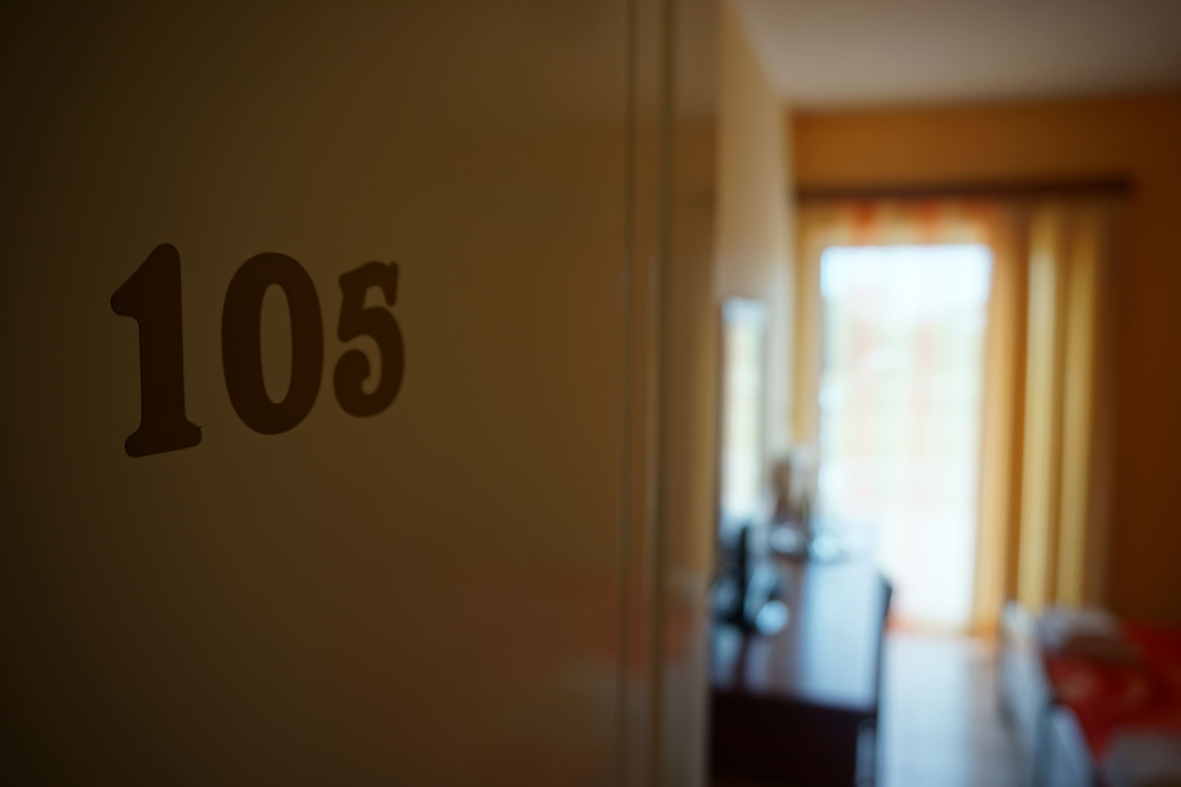 Primer plano del número de habitación '105' en una pared.