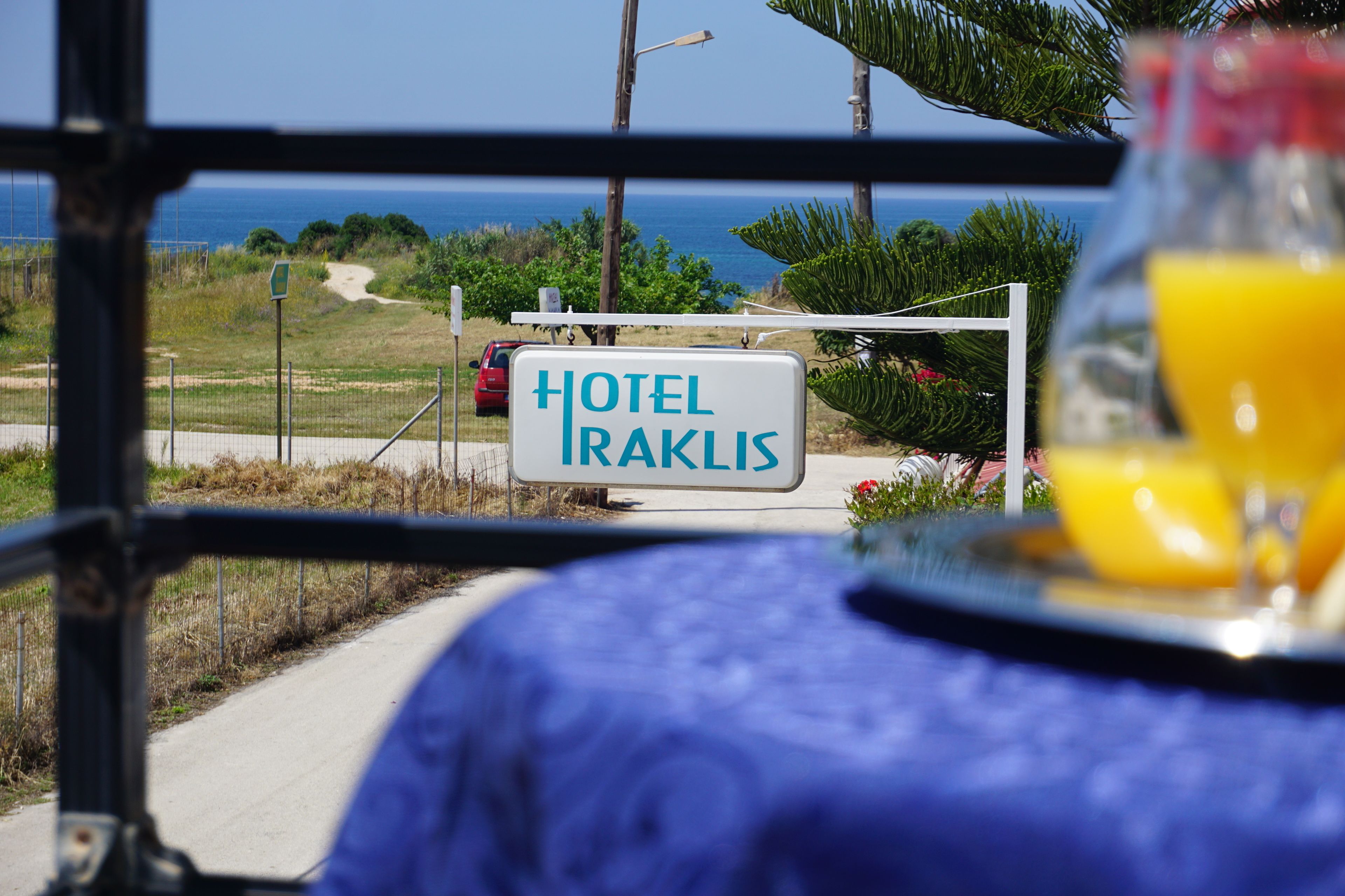 A sign for Hotel Iraklis with a view of the sea and a pathway.
