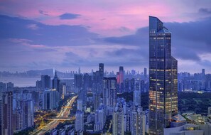 Une vue urbaine avec un gratte-ciel imposant, des bâtiments urbains denses et une rivière en arrière-plan.