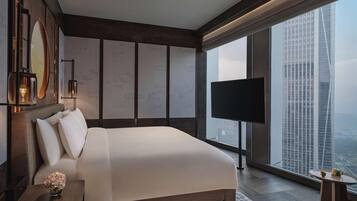 A modern hotel room with a large bed, a TV, and a city view.