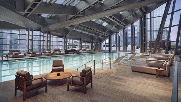 A modern indoor pool area with a glass ceiling, lounge seating, and a view of the cityscape. - Park Hyatt Shenzhen (Shenzhen)