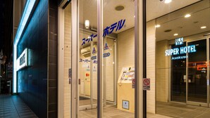 A hotel entrance with glass doors, a reception desk, and a sign for the Super Hotel Asakusa. - Super Hotel Asakusa (Tokyo)