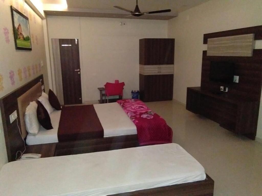 A hotel room with two beds, a TV, a wardrobe, and a ceiling fan.