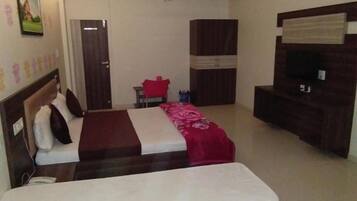 A hotel room with two beds, a TV, a wardrobe, and a ceiling fan.