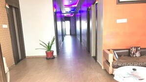 A hotel corridor with a reception area on the right, featuring a sofa and a table. - Hotel Atithi (Mahesana)
