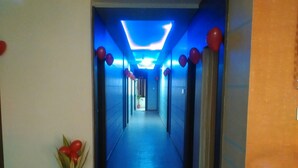 A hallway with a blue-lit ceiling, red balloons, and a potted plant. - Hotel Atithi (Mahesana)